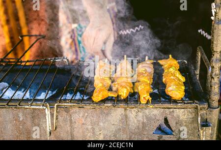 Crop unkenntlich Person Drehen Spieß Fleisch beim Kochen auf dem Grill Stockfoto