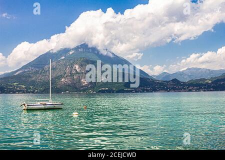 Blick auf Segelboot verankert im Hafen das Dorf Varenna am Comer See. Landschaftlich reizvolle Landschaft im Hintergrund alpen Berge, Bäume und Wasser. Mailand Stockfoto