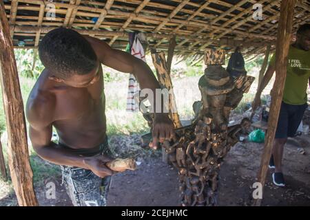 Afrikanischer Mann mittleren Alters in der Tischlerwerkstatt, afrikanische Kunstfiguren mit einfachem Handwerkzeug zu machen Stockfoto