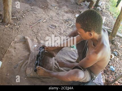 Afrikanischer Mann mittleren Alters in der Tischlerwerkstatt, afrikanische Kunstfiguren mit einfachem Handwerkzeug zu machen Stockfoto