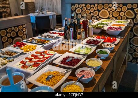 Ein Salatbuffet mit einer Auswahl an exquisiten Olivenölen und Balsamico-Essigen ist im Hotel Cresta Palace in Celerina, Schweiz, aufgebaut. Tomate und Mozzarella, Rote Bete, Gurke und Süßmais gehören zu den ausgestellten Gerichten. Stockfoto