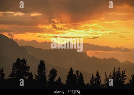 Malerischer Blick auf die helle Sonne über Bergrücken und aufgehen Wald am bewölkten Morgen Stockfoto