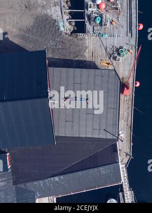 Drohnenansicht von Reisenden, die auf Deck des Stadthafens im Sonnenlicht liegen, Lofoten Inseln, Norwegen Stockfoto