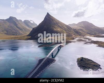 Malerische Drohne Blick auf Berge und Fahrbahn mit Brücke läuft Unter blauem Ozeanwasser der Lofoten Inseln Stockfoto