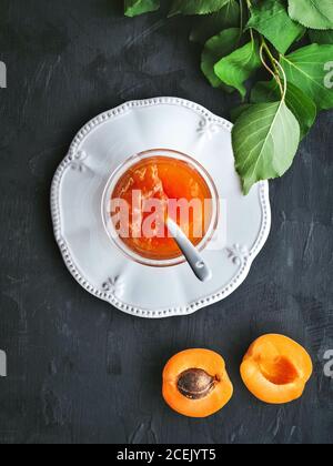 Frische Aprikosen in zwei Hälften geschnitten und Aprikosenmarmelade im Glas. Overhead-Aufnahme mit Kopierplatz. Stockfoto