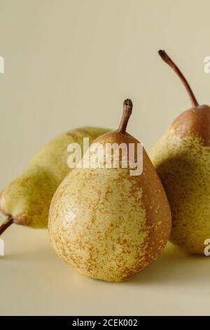 Glänzende beige farbige reife saftige Birnen auf einfachem grauen Hintergrund Stockfoto