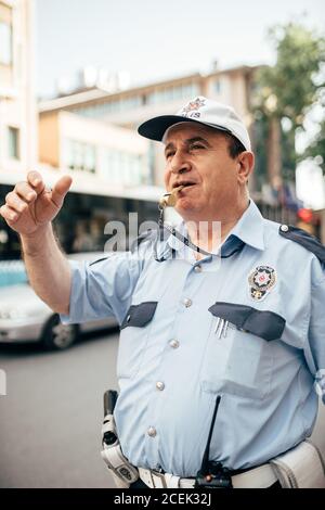 Istanbul, Türkei - August 20 2018: Erwachsener Mann in Polizeiuniform, der auf der Stadtstraße steht und pfeift Stockfoto