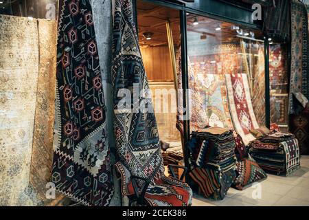 Verschiedene verzierte Teppiche liegen in der Nähe von kleinen Laden auf dem Markt in Istanbul, Türkei Stockfoto