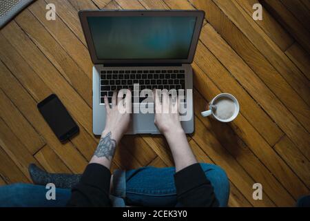 Von oben Ernte unkenntlich Frau auf dem Boden sitzen und tippen auf dem Laptop. Stockfoto