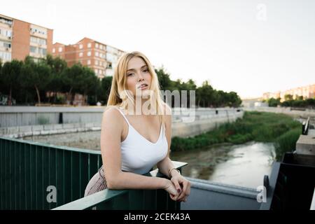 Junge Frau, die sich auf das Brückengeländer stützt Stockfoto