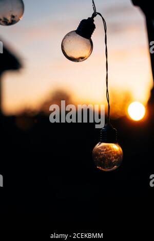 Lichterketten in Form von Kugeln, die bei Sonnenuntergang hängen Unscharfer Hintergrund Stockfoto