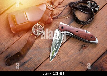 Viele Herrenartikel auf Holzbrett, Nahaufnahme bei Edelstahl Klappmesser. Stockfoto