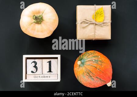 Kürbisse, Geschenk in einer Schachtel und Kalender auf schwarzem Hintergrund. Draufsicht, flach liegend. Herbst, Thanksgiving Konzept Stockfoto