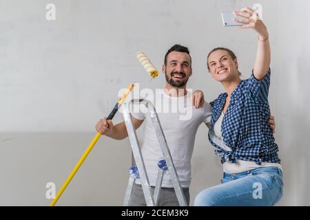 Eine Frau macht mit einem Mann ein Foto am Telefon. Sie halten eine Rolle Stockfoto