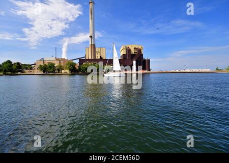 Michigan City, Indiana, USA. Ein Segelboot fährt durch die Michigan City Generating Station am Ufer des Lake Michigan. Stockfoto