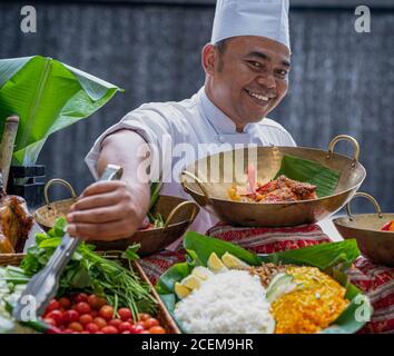 Portrait des asiatischen Küchenchefs mit köstlichen Gerichten Stockfoto