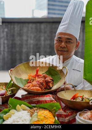 Portrait des asiatischen Küchenchefs mit köstlichen Gerichten Stockfoto
