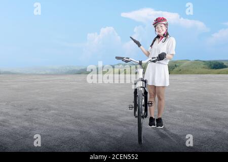 Asiatische Frau mit einem Fahrradhelm neben ihrem Fahrrad stehen Auf der Straße Stockfoto