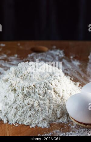 Mehl und Eier werden für den Teig auf einem hölzernen Hintergrund zubereitet. Stockfoto