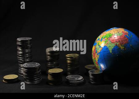 Vorratsstapel von 1, 2, 5, 10 Indische Rupie Metall Münze Währung mit Globus isoliert auf schwarzem Hintergrund. Finanz-, Wirtschafts-, Investitionskonzept. Stockfoto