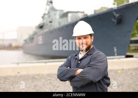 Porträt des ersten Marinemataten, der in der Nähe eines großen Schiffes im Hintergrund steht. Stockfoto