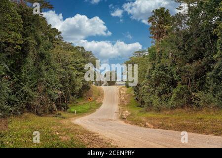 Eine Landstraße führt über einen Hügel mit einem Pfeilzeichen für eine kurvenreiche Straße in der Ferne Stockfoto