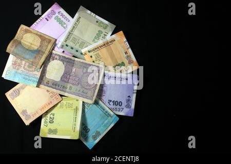 Jetzt und alte indische Währungen. 50, 100, 200, 500, 2000 Rupien-Scheine und Münzen. Indische Währung auf schwarzem Hintergrund isoliert. Stockfoto