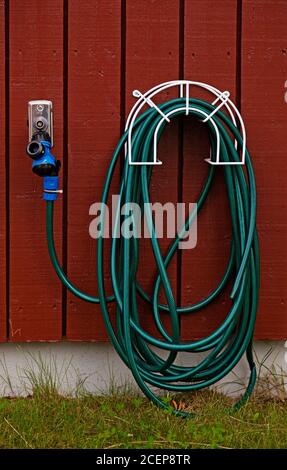 Grüner Wasserschlauch, der an der Wand hängt Stockfoto