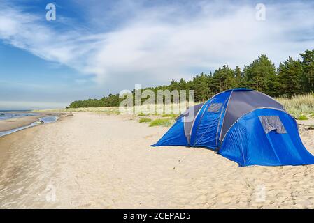 Blaues Camping-Zelt am Sandstrand an der Küste. Abenteuer-Reisekonzept mit Kopierraum. Zelt im Sommer Sonnentag am ostseestrand auf der Insel Aegna, Stockfoto