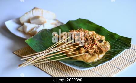 Sate Padang oder Padang Satay und Ketupat (traditioneller Reiskuchen) auf Bananenblatt. Stockfoto