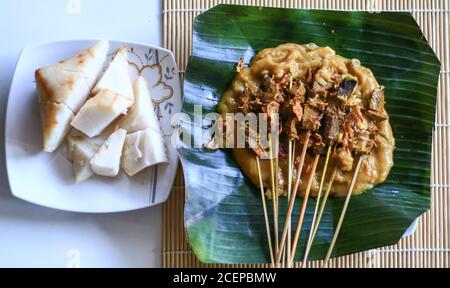 Sate Padang oder Padang Satay und Ketupat (traditioneller Reiskuchen) auf Bananenblatt. Stockfoto