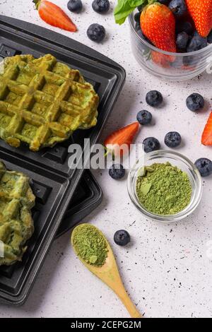 Selektiver Fokus, grüne Quark-Waffeln mit Matcha und frischen Beeren auf hellem Hintergrund Stockfoto