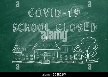 Schulgebäude und Schriftzug COVID-19 Schule geschlossen auf grüner Tafel. Handgezeichnete Skizze. Coronavirus-Konzept. Stockfoto
