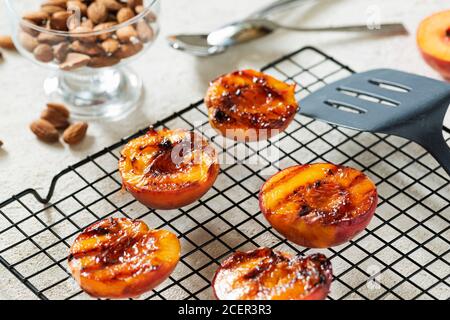 Gegrillte Pfirsiche Sommer Dessert American bbq. Serviert mit Mandeln, Eis und Keksbröseln. Nahaufnahme Stockfoto