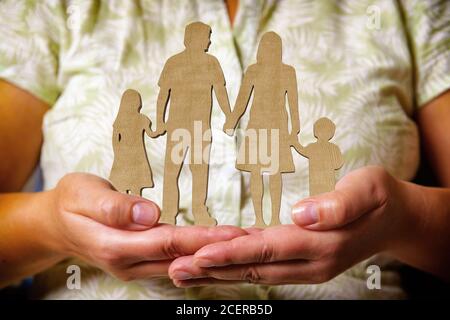 Holzfiguren - Familie, Kinder und Eltern in einer Linie, die Hände hält und in den Händen einer Frau steht Stockfoto