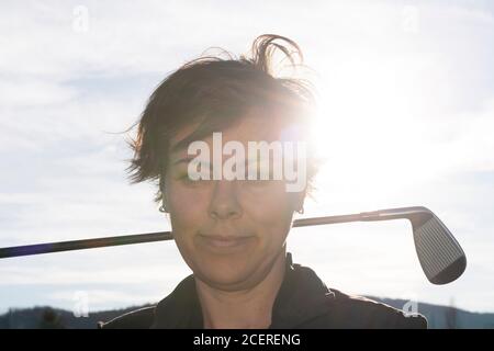 Golfer Leaning ihren Golfclub auf ihren Schultern mit Sonnenlicht. Stockfoto