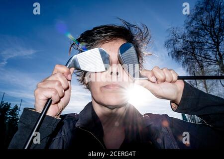 Golfer hält ihre Golfschläger vor ihren Augen mit Sonnenlicht. Stockfoto