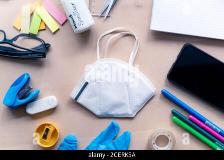 Nahaufnahme der Gesichtsmaske auf Holz Schreibtisch im Klassenzimmer mit Handy und Block Notizen und Bildungseinrichtung. Konzept der Prävention von covid in der Schule Stockfoto