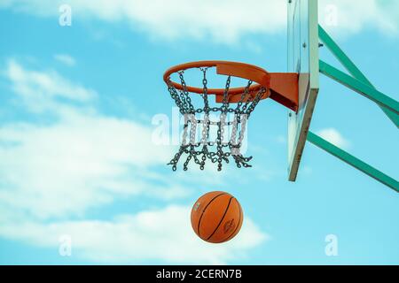 Wurfbasketball fliegt durch den Kettenkorb. Stockfoto