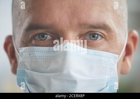 Horizontale Nahaufnahme Portriat Aufnahme von unkenntlichen kaukasischen Mann trägt Schutz Maske auf seinem Gesicht und Blick auf die Kamera Stockfoto