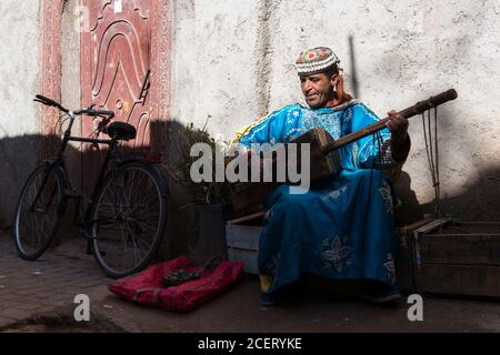 Musiker, der auf einem Gimbi (alias sintir) auf einer Straße in der Medina, Marrakesch, mit Gnawa-Musik unterwegs ist. Stockfoto