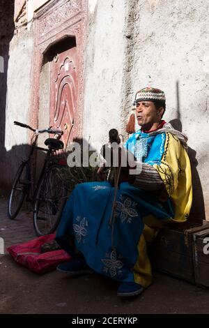 Musiker, der auf einem Gimbi (alias sintir) auf einer Straße in der Medina, Marrakesch, mit Gnawa-Musik unterwegs ist. Stockfoto