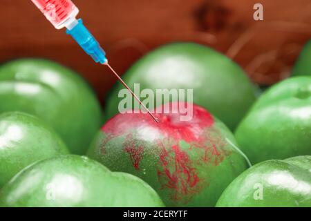 Eine Chemikalie, die in die grüne Frucht des Nektarins injiziert. Das Konzept der GVO-Lebensmittel, Gemüse und Obst Regenbogen. Nahaufnahme. Stockfoto