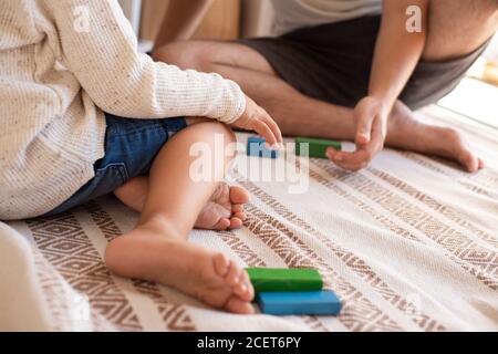 Kleines Kind und sein Vater spielen zu Hause mit Holzbausteinen. Heimschooling. Bleiben Sie zu Hause. Zeit mit der Familie Stockfoto