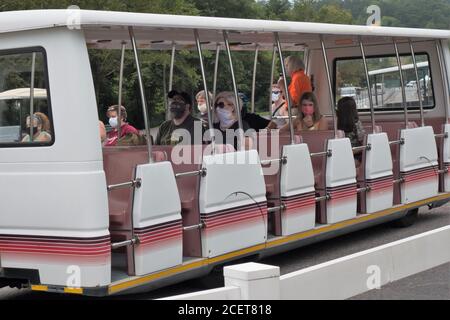 Menschen, die Gesichtsmasken tragen und sozial distanziert sind, fahren mit der Straßenbahn nach Dollywood in Pigeon Forge, TN, USA. Stockfoto