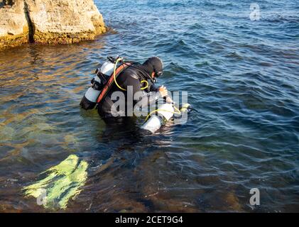 Menschen in Neoprenanzügen und Tauchausrüstung bereiten sich darauf vor, ins Wasser zu tauchen. Stockfoto