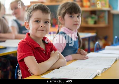Weißrussland, die Stadt Gomil, 30. Mai 2019. Fotoshooting im Kindergarten. Schöner Junge Vorschulkinder an seinem Schreibtisch. Stockfoto