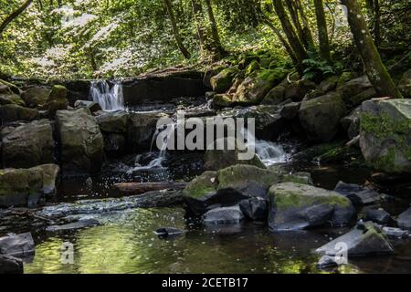 Flusslauf übersät mit Felsen mit Wasserfall im Siegerland Stockfoto