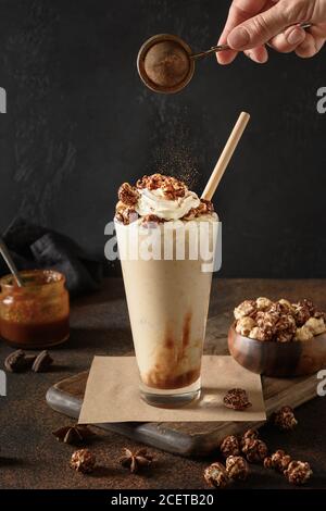 Banana Milkshake Karamell und Schlagsahne bestreut Kakaopulver auf dunkel garnieren. Stockfoto