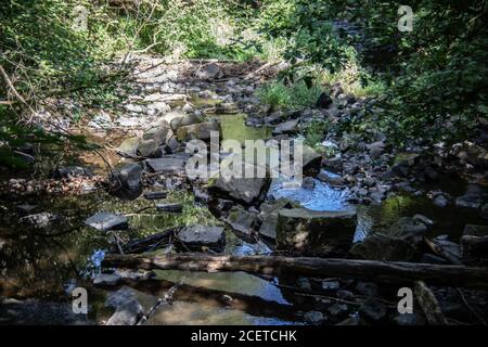 Flusslauf übersät mit Felsen mit Wasserfall im Siegerland Stockfoto